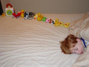 Boy sleeping with toys lined up in a row